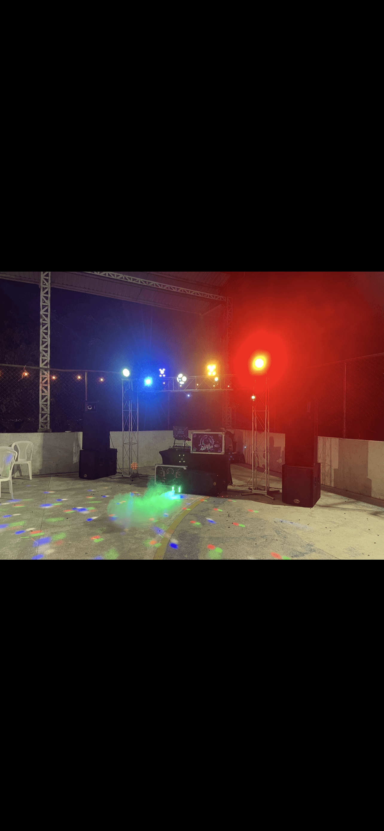 Montaje de DJ con luces de colores, altavoces y humo en pista de baile nocturna.